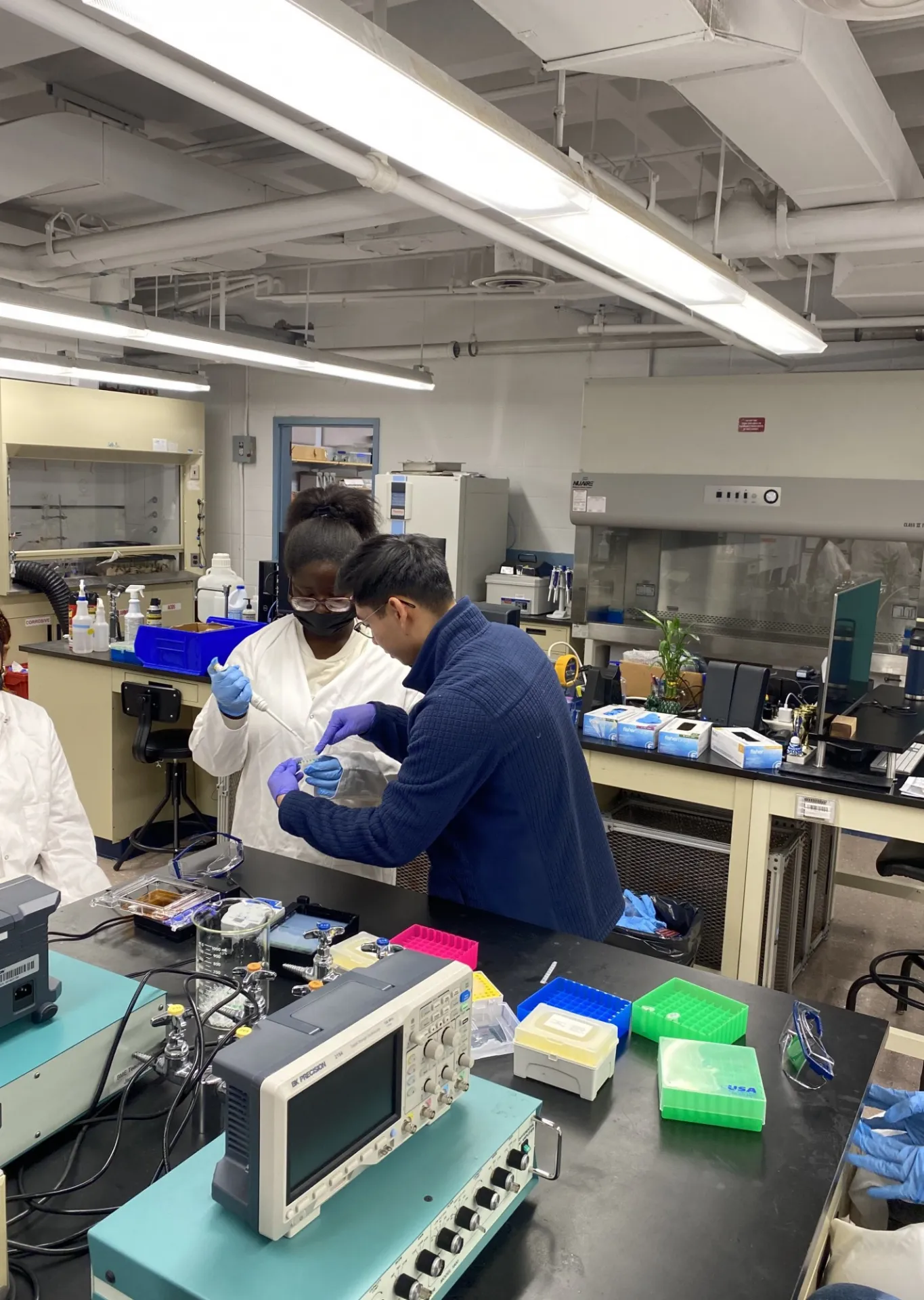 Instructor Dennis Zhang guides a student in using a micropipette to load experimental samples into a gel electrophoresis machine. Photo Credit: Sophia Sorid